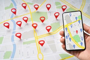 Person holding a smartphone above a road map with red navigation pins