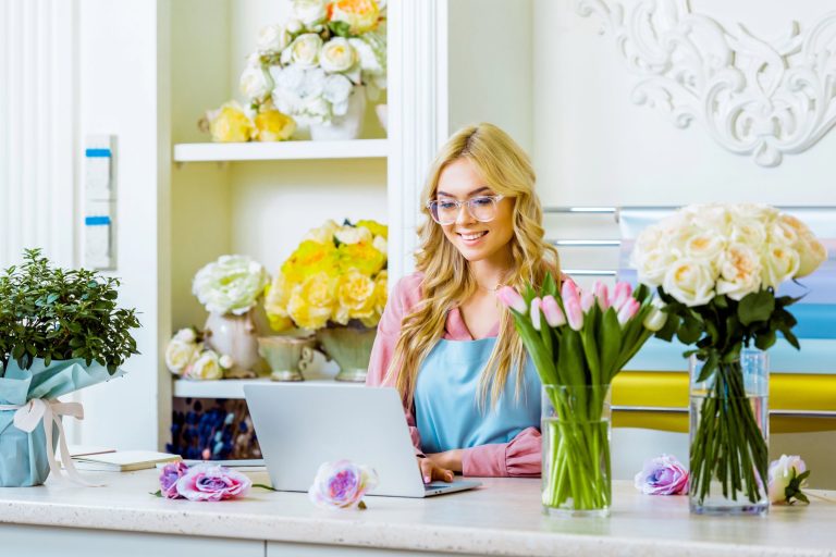Small business owner reviewing online business listings on a laptop at a shop counter